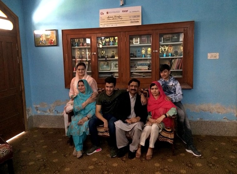 Image: Malala Yousafzai, second right, poses in her old home with family and with Pakistan's Information Minister Marriyum Aurangzeb in the center.