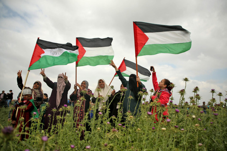 Image: Palestinian women wave Palestinian flags and flash the victory gesture during a protest near the border with Israel east of Jabalia in the Gaza strip, commemorating Land Day on March 30, 2018.