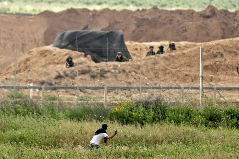 A Palestinian throws stones at Israeli soldiers across the border on March 30.