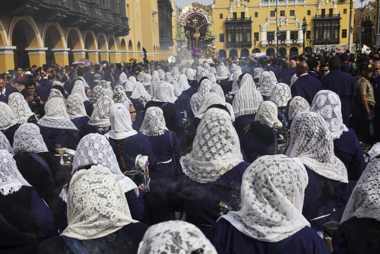 Image: Women, their heads covered by veils, burn incense