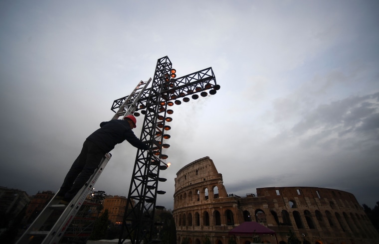 Image: A worker lights the cross before the arrival of Pope Francis for the Via Crucis