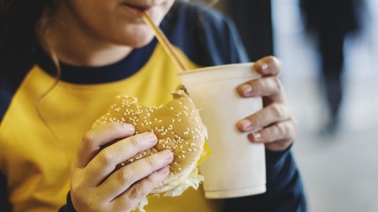 Close up of teenage girl eating hamburger obesity concept