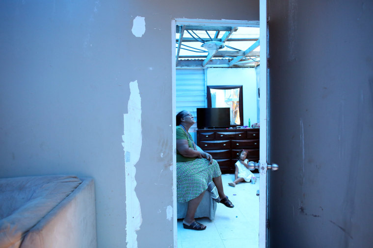 Image: Milagros Nolazco sits in her bedroom and near her granddaughter Isya, as a plastic sheet replaces the roof hit by Hurricane Maria in September, in a neighbourhood in Canovanas
