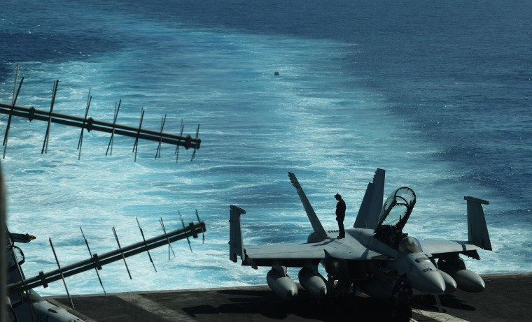 Image: A sailor inspects atop an FA-18 hornet fighter jet