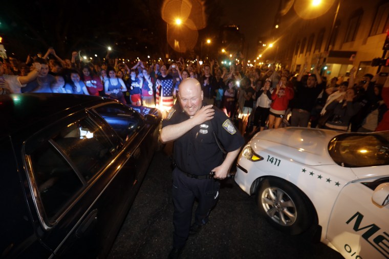 A police officer and a woman react to news of the arrest of one of the Boston Marathon bombing suspects, Friday, April 19, 2013, in Boston. Boston Marathon bombing suspect Dzhokhar Tsarnaev was captured in Watertown, Mass. The 19-year-old college student wanted in the bombings was taken into custody Friday evening after a manhunt that left the city virtually paralyzed and his older brother and accomplice dead. (AP Photo/Julio Cortez)