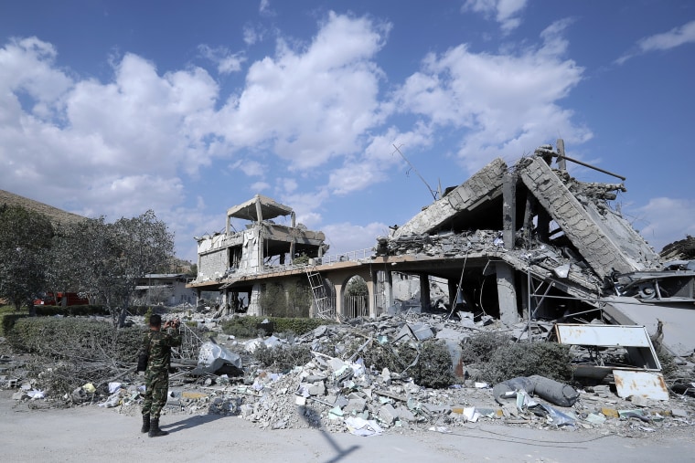 Image: A Syrian soldier films the damage of the Syrian Scientific Research Center