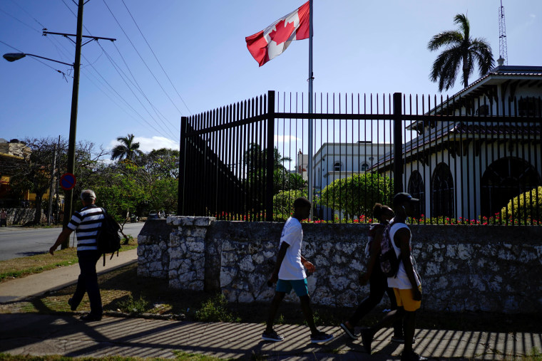 Image: People pass by the Canada's Embassy in Havana