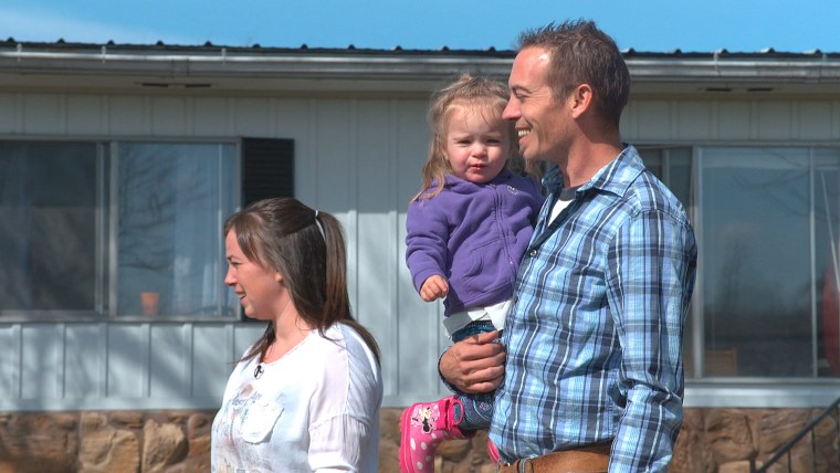 Image: Lelah and Jade Jerger of Indiana with their daughter Jaeleh in their front yard waiting for her siblings to arrive home from school.