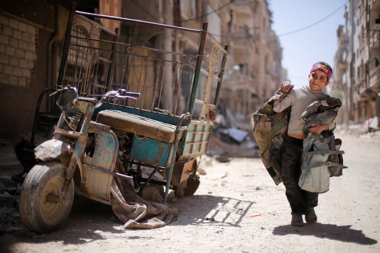 Image: A boy walks along a damaged street at the city of Douma in Damascus