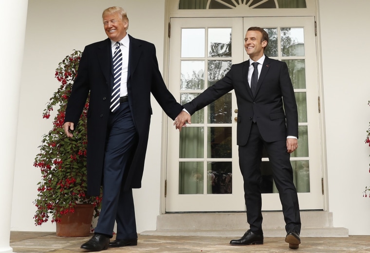 Image: U.S. President Trump and French President Macron hold hands as they walk down the colonnade past the Rose Garden at the White House in Washington