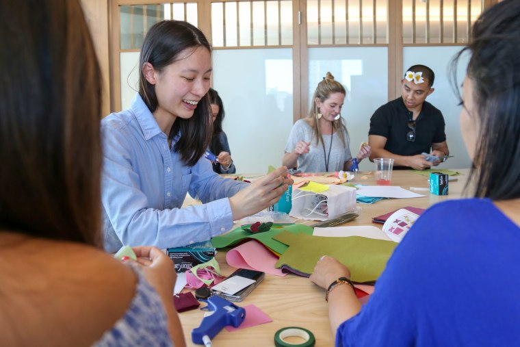 Pinterest software engineer Kim Toy (left) leads her fellow Pinterest employees in a lesson about making flower crowns and lapels out of colorful felt and hot glue.