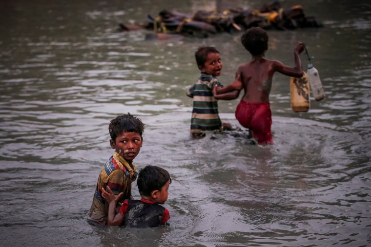 Image: Rohingya siblings fleeing violence hold one another as they cross the Naf River