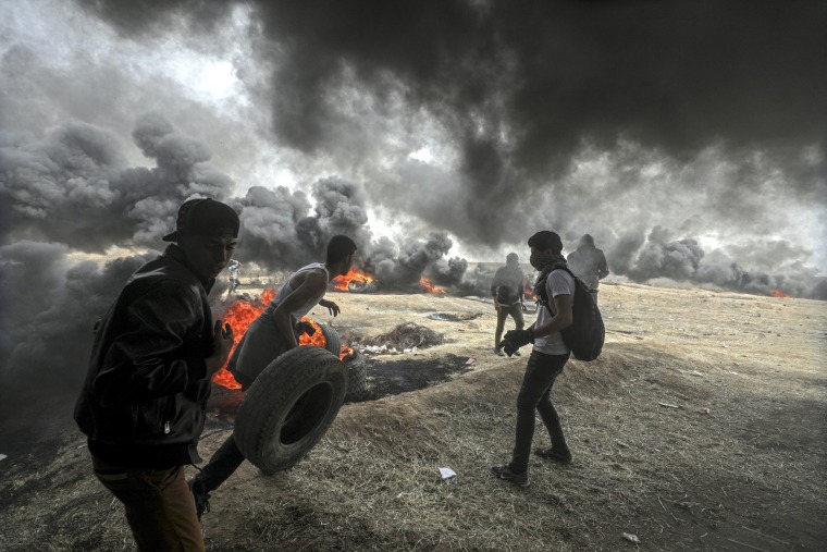 Image: Palestinians protesters burn tires during clashes near the border with Israel