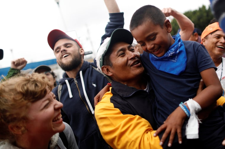 Image: A man and his son, members of a caravan of migrants from Central America, react near the San Ysidro checkpoint in Tijuana
