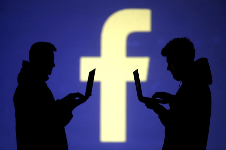 Image: FILE PHOTO: Silhouettes of laptop users are seen next to a screen projection of Facebook logo in this picture illustration