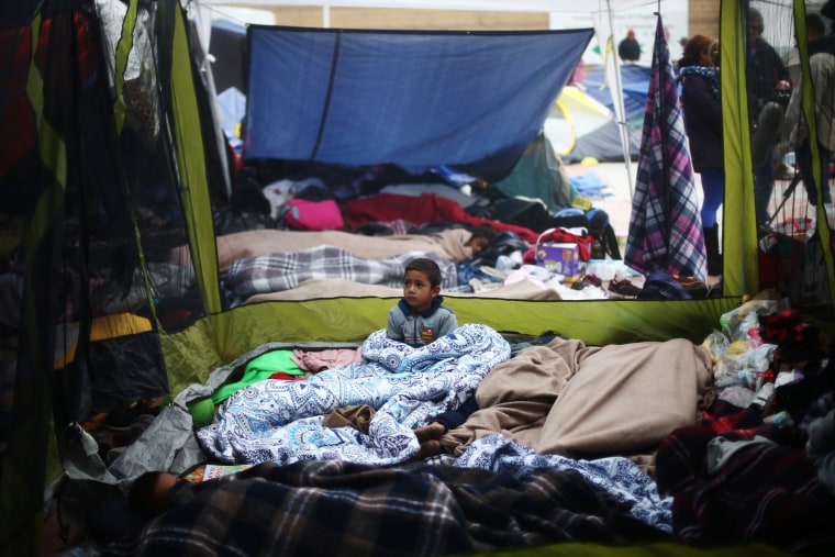 Image: A child traveling with a caravan of migrants from Central America sits at a camp near the San Ysidro checkpoint, after U.S. border authorities allowed the first small group of women and children entry from Mexico overnight, in Tijuana