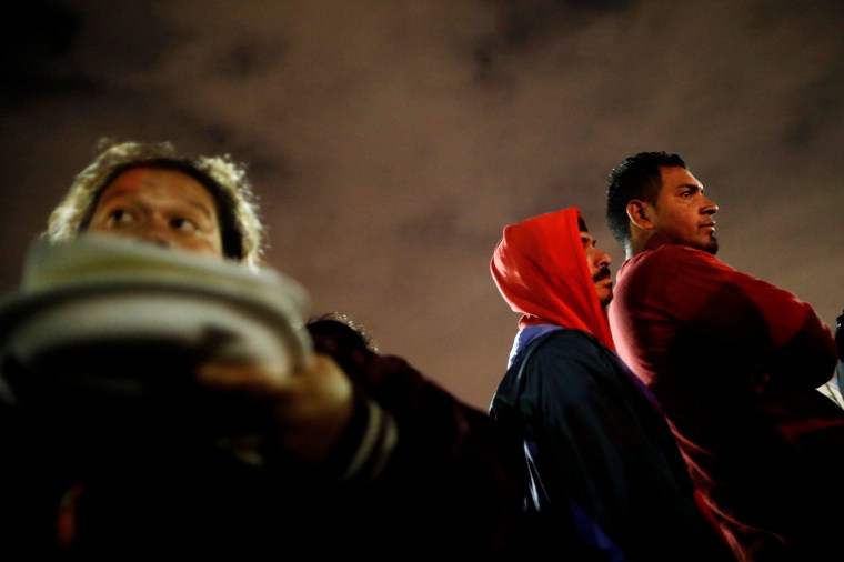 Image: People traveling with a caravan of migrants from Central America line up for eat at a camp near the San Ysidro checkpoint, after U.S. border authorities allowed the first small group of women and children entry from Mexico on Monday night, in Tijua