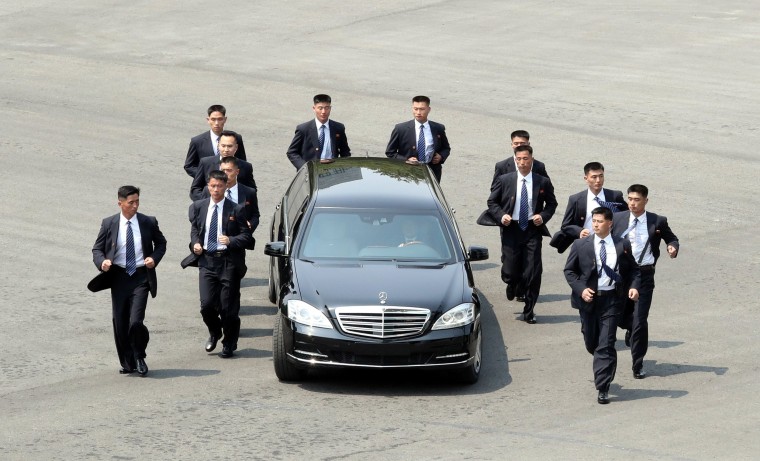 Image: Bodyguards escort a car carrying North Korean leader Kim Jong Un