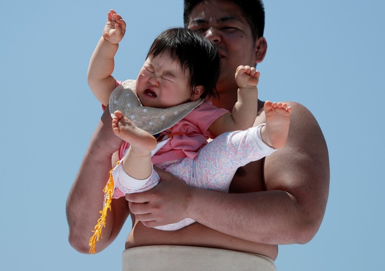 Image: A baby cries in the arms of an amateur sumo wrestler during a baby crying contest at Sensoji temple in Tokyo