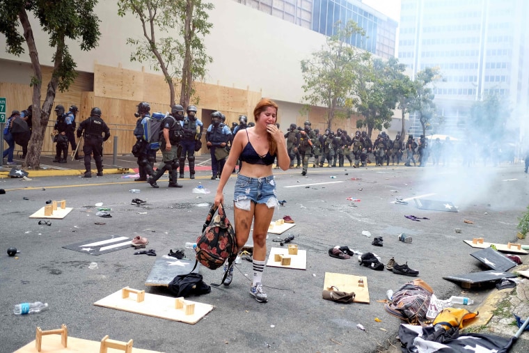 Image: A woman cries in front of a riot police line after tear gas was deployed during a May Day