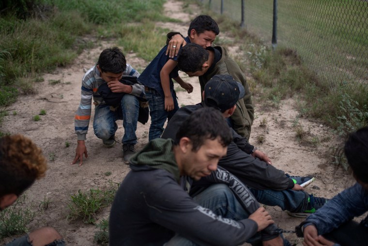Image: A four-year-old boy weeps in the arms of a family member as he and others were apprehended by border patrol agents