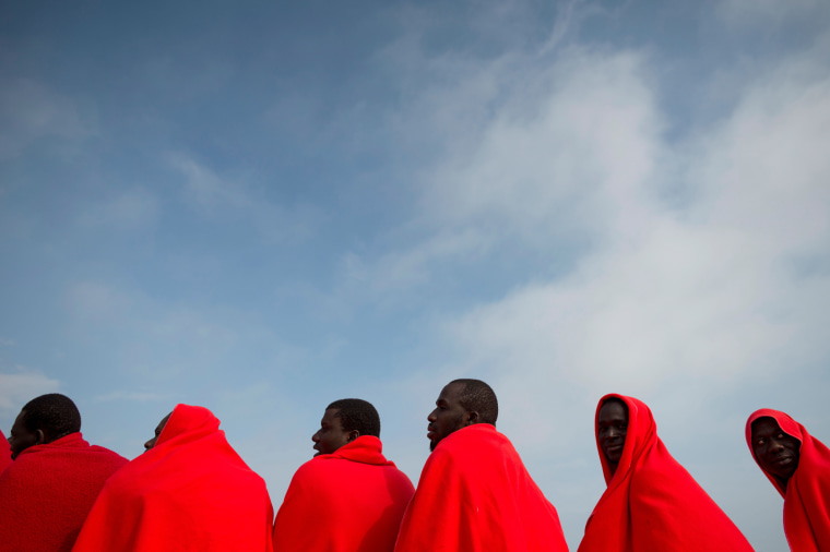 Image: A group of migrants warm up with Red Cross blankets