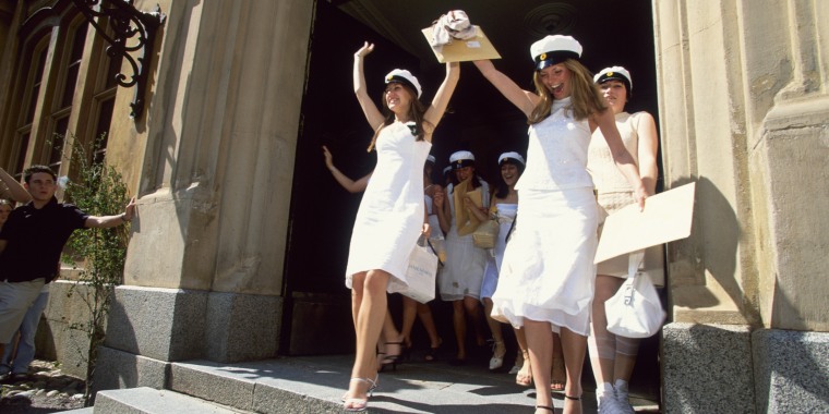 Women graduate in white dresses and matching white caps.