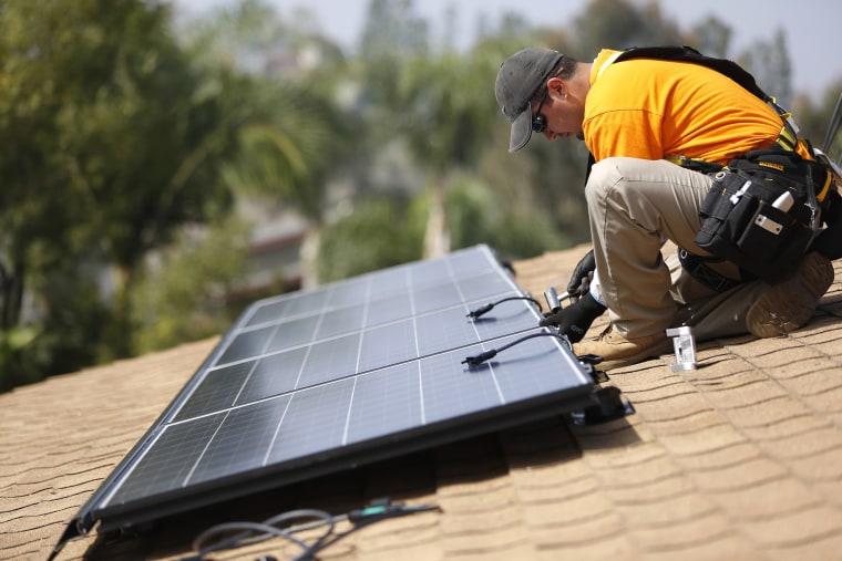 Image: Vivint Solar technician Aguilar installs solar panels on the roof of a house in Mission Viejo