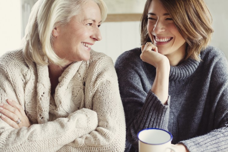 Image: Laughing mother and daughter in sweaters drinking coffee