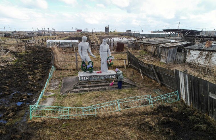 Image: A woman cleans the World War II monument in Irkutskoye