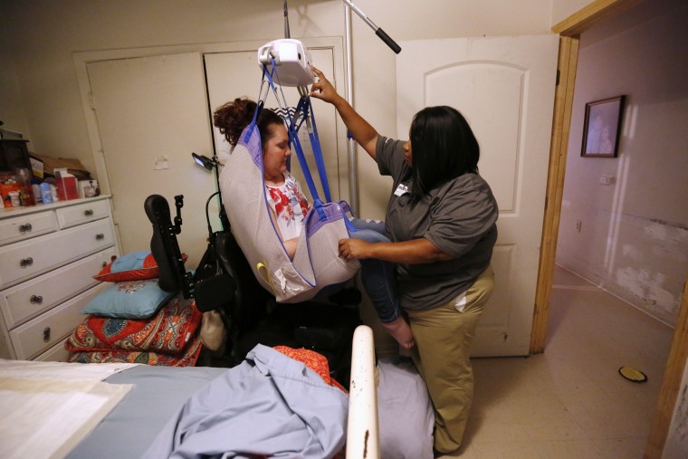 Image: Shonta Faulk uses a harness to get Jamie Duplechine into bed