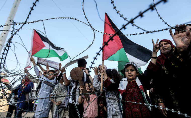 Image: Palestinians stand near fence between the Gaza Strip and Israel