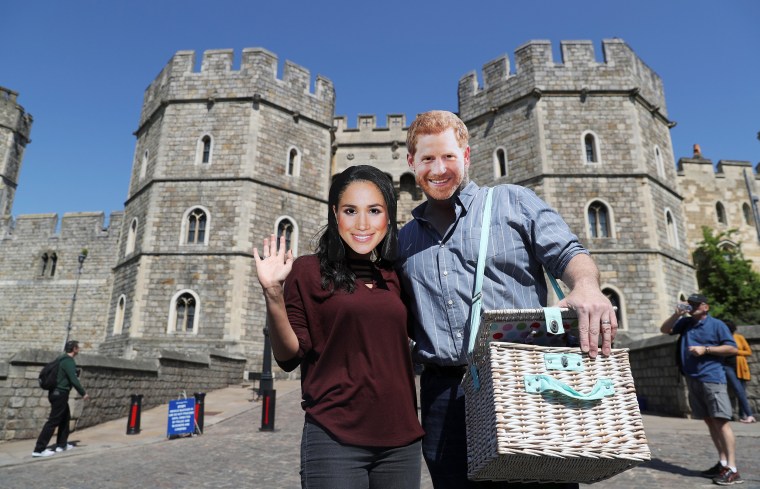 Image: A couple wear Prince Harry and Meghan Markle face masks outside Windsor Castle, in Windsor