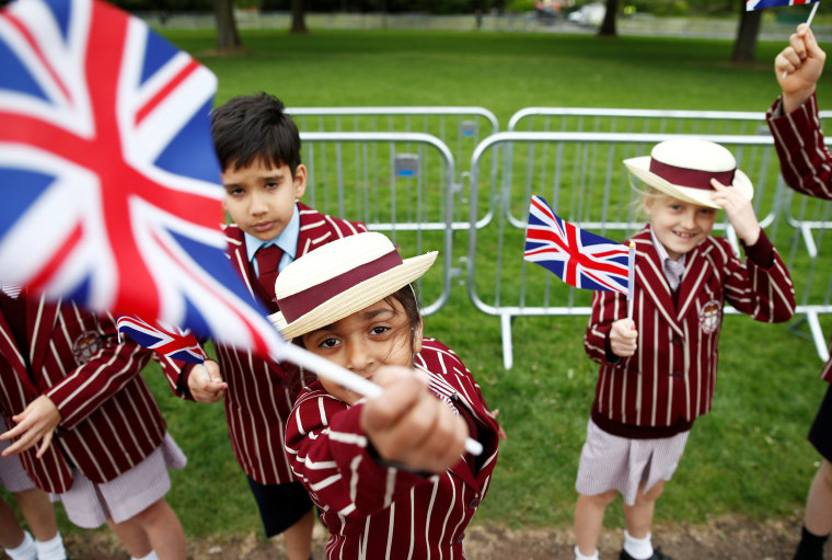 Image: School children in uniform wave Union Jack Flags