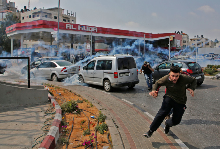 Image: Palestinians run away from tear gas shot at them by Israeli forces during a protest in Ramallah