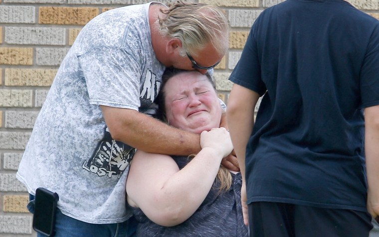 A man hugs a woman outside the Alamo Gym where parents wait to reunite with their children.