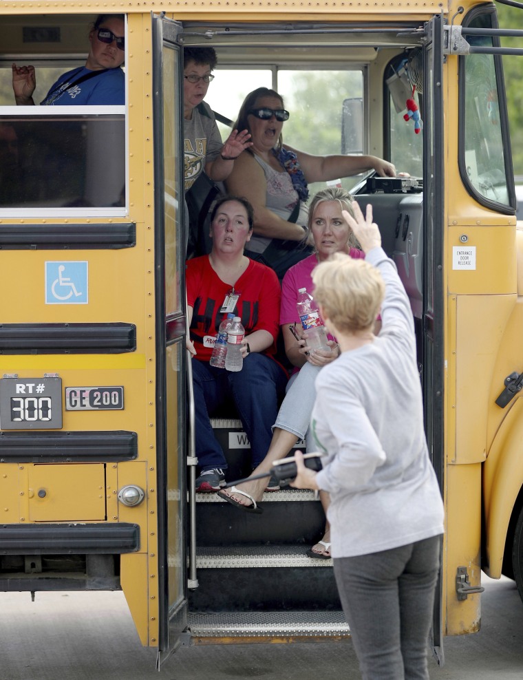 School staff members sit in a school bus to be transported to another school.