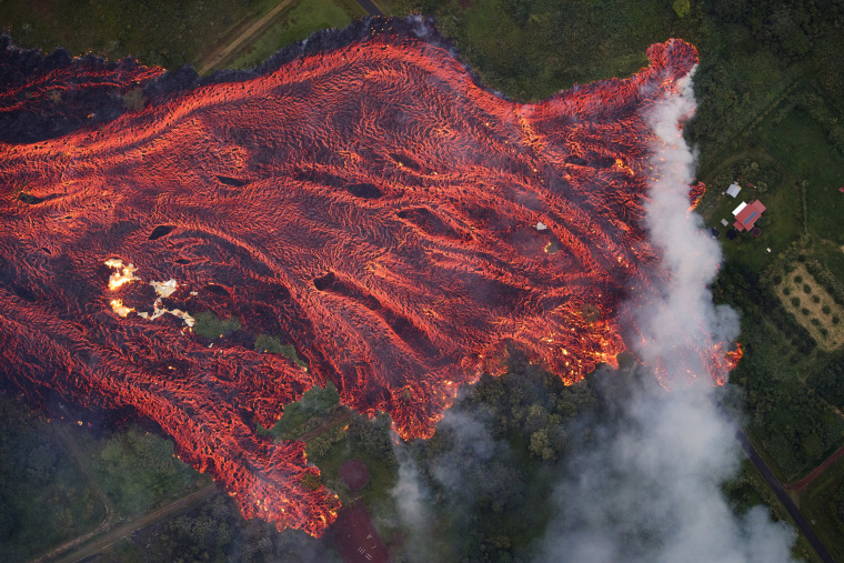 Image: A massive fast moving lava flow consumes everything in its path, as the flames from the remnants of one home burns on the left, while it approaches another on the right in Pahoa, Hawaii, May 19, 2018.