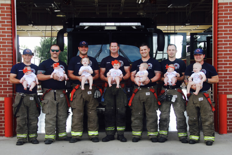 Seven firefighters with their babies pose for picture