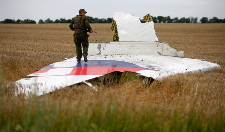 Image: An armed pro-Russian separatist stands on part of the wreckage of MH17 three days after it was brought down in July 2014.