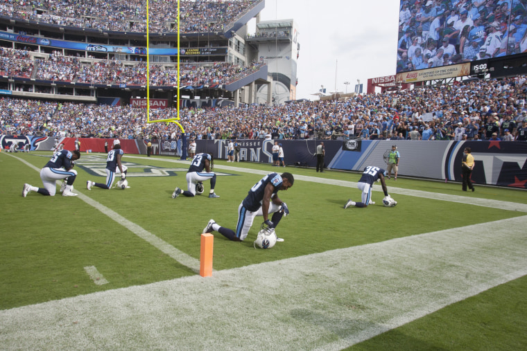 Image: Members of the Tennessee Titans kneel at the end zone