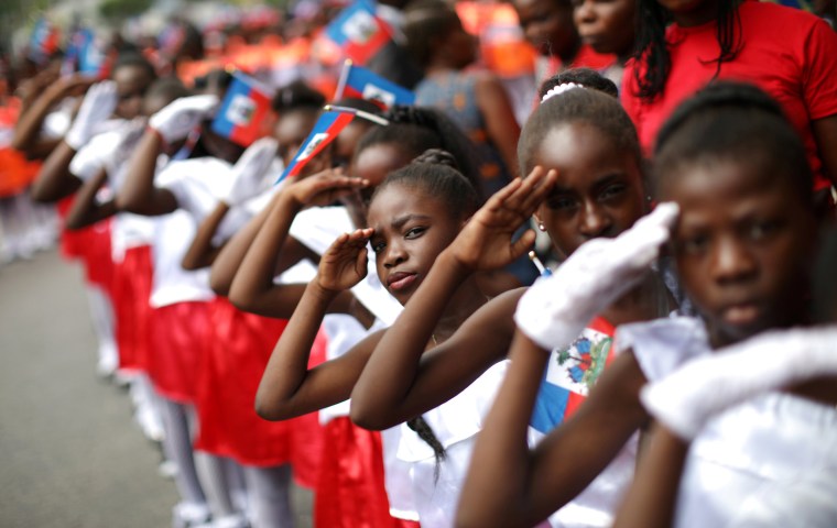 Image: Girls salute during celebrations for National Haitian Flag Day in the streets of Petion Ville, Port-au-Prince