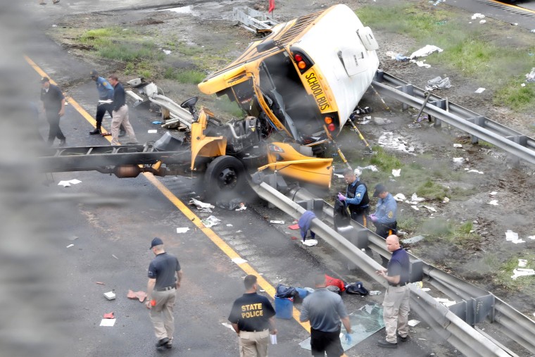 Image: Police stand near the wreckage of a school bus on Interstate 80 following an accident with a dump truck in Mount Olive Township
