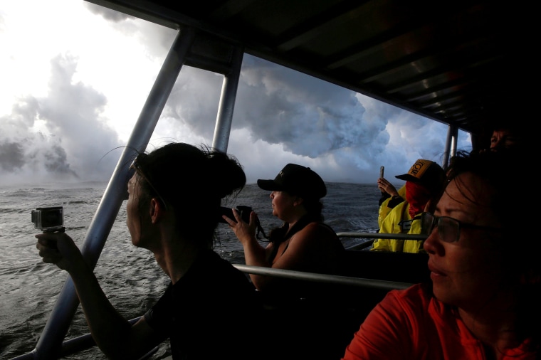 Image: FILE PHOTO: People watch as lava flows into the Pacific Ocean southeast of Pahoa