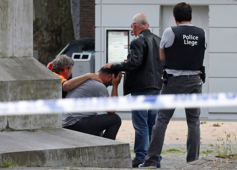 Image: A man is being consoled at the scene of a shooting in Liege