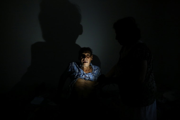 Image: Cancer patient Israel Gonzalez poses for a photograph with the light of a solar lamp at his home as the island's fragile power system is still reeling from the devastation wrought by Hurricane Maria eight months ago, in Utuado