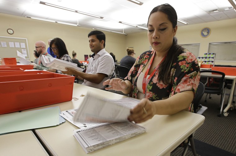 Image: Bianca Savola inspects a mail-in ballot in Sacramento