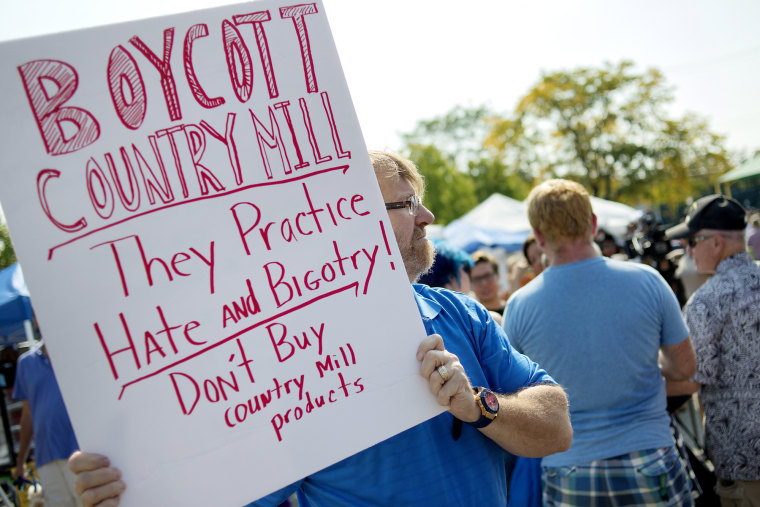 Image: Lansing resident Kennan DeWitt holds up a sign near the Country Mill booth in protest on Sunday, Sept. 17, 2017, at the East Lansing Farmer's Market.