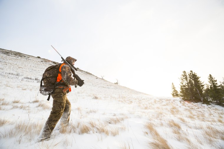 Image: A male hunter at sunrise in the snow.