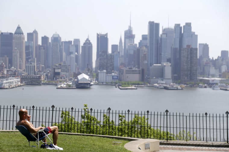 Image: A man enjoys the sunshine and the New York City skyline from a park